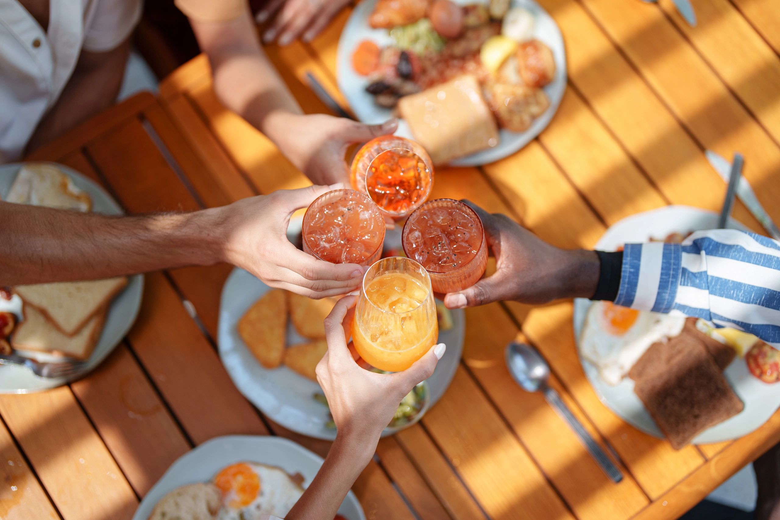 Friends raising glasses over breakfast spread