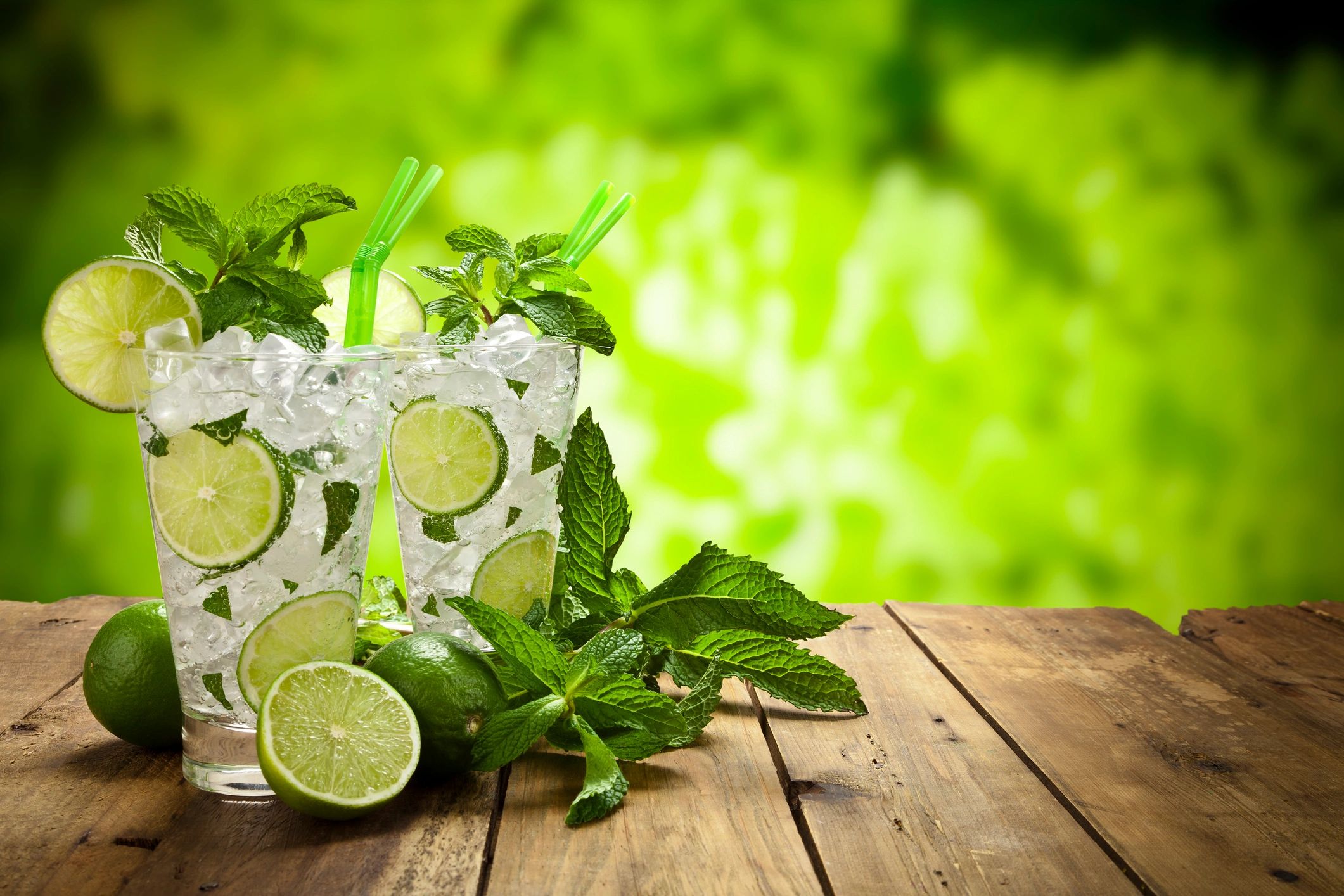 Two mojito cocktails on a rustic wooden table